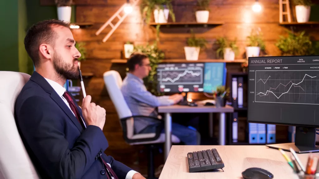 Businessman thinking in front of his monitors in the office late at night